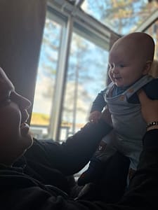 Minusta Niko Seppänen katselemassa läsnäolevasti vauvaansa sylissä Keski-Suomessa.